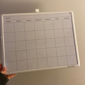 White board with the month and days, has a holder for dry erase marker